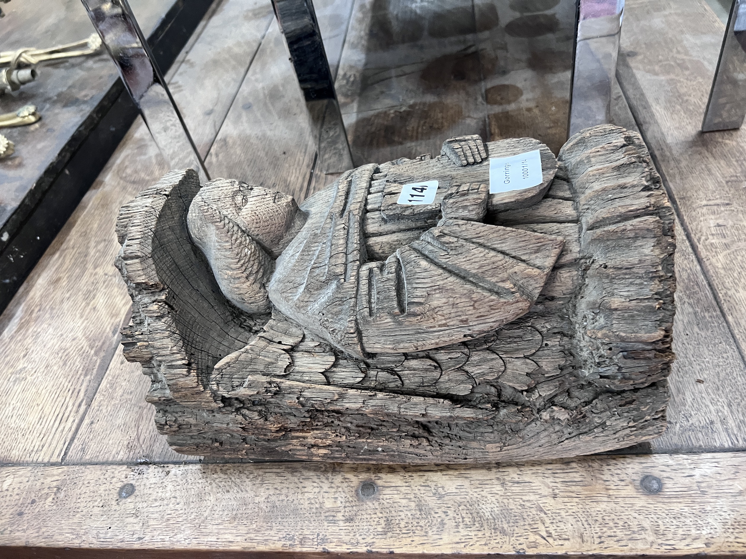 A late 16th carved pine misericord, modelled as a bishop holding a plaque, height 36cm